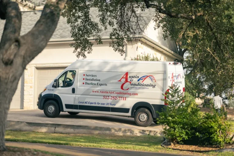 White van with "Austin Air Conditioning" logo parked in a driveway near a house, surrounded by trees and greenery.